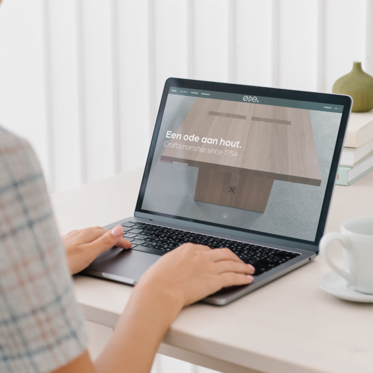 Mock-up afbeelding met een tafel waarop een laptop staat. Op het beeldscherm staat een printscreen van de homepage van ODE Design.