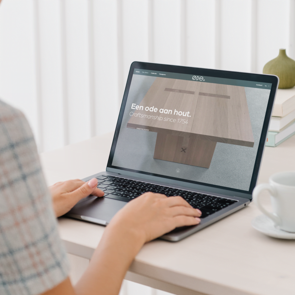 Mock-up afbeelding met een tafel waarop een laptop staat. Op het beeldscherm staat een printscreen van de homepage van ODE Design.